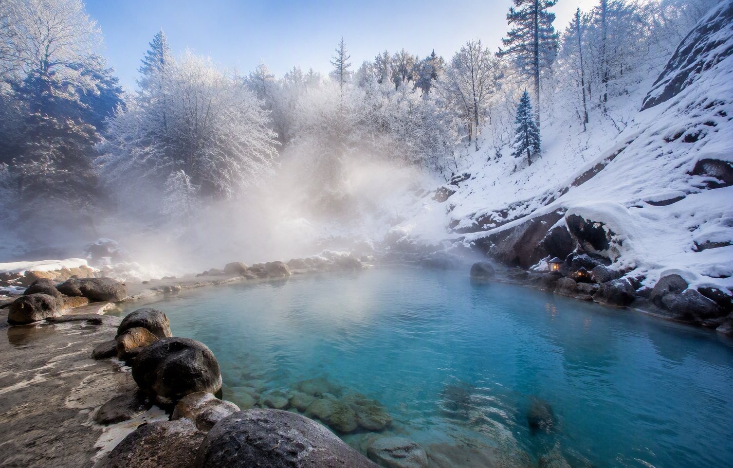 Volcanic hot springs — 40°C water steaming in the snow, frost forming on your hair