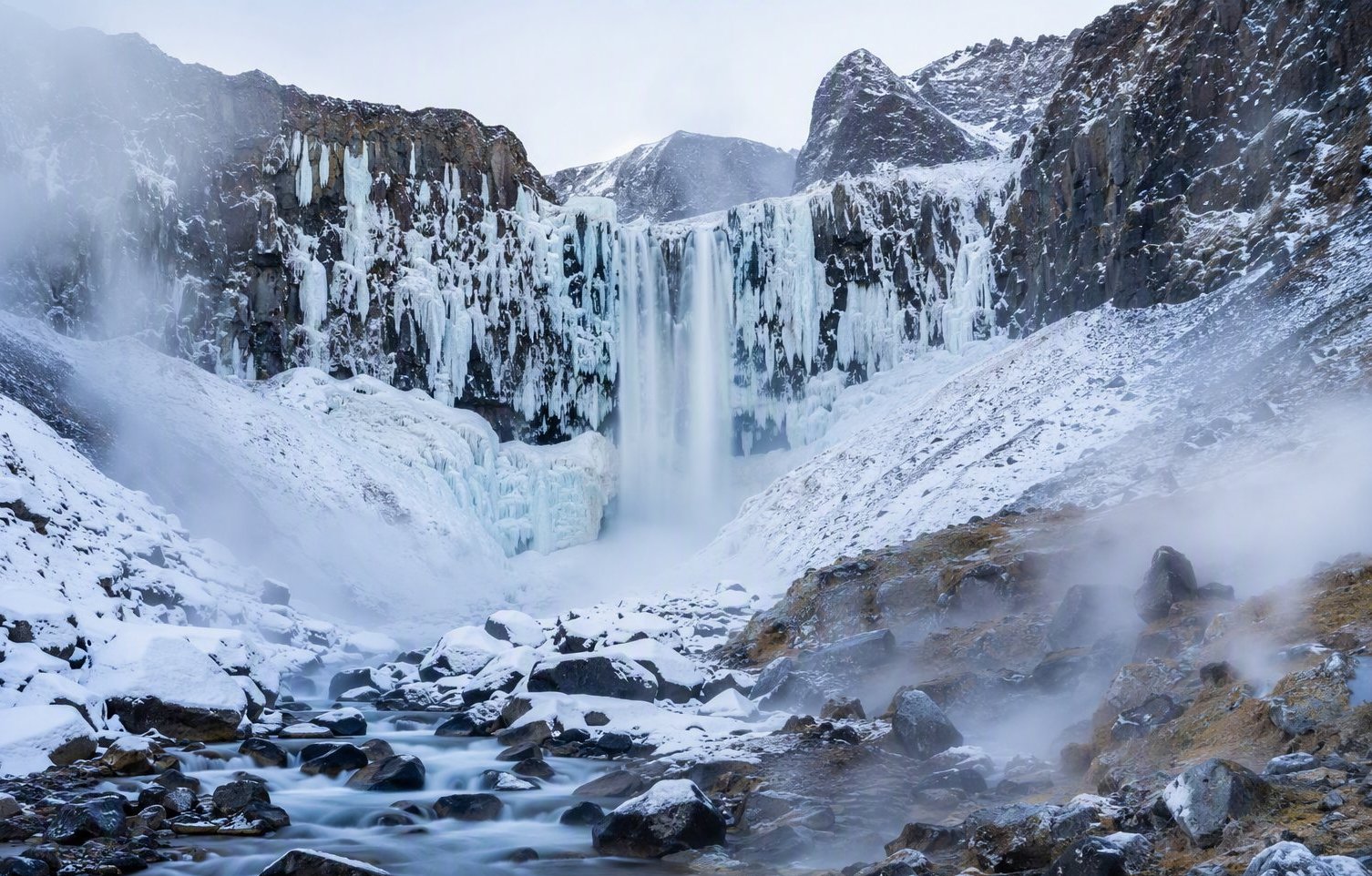Changbai Waterfall — a 68-meter drop half-frozen in ice, water rushing beneath